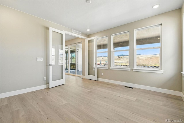 unfurnished room featuring baseboards, french doors, visible vents, and light wood-type flooring