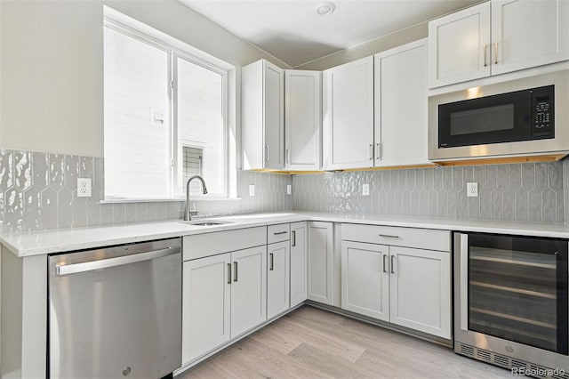 kitchen featuring stainless steel dishwasher, wine cooler, built in microwave, light wood-style flooring, and light countertops