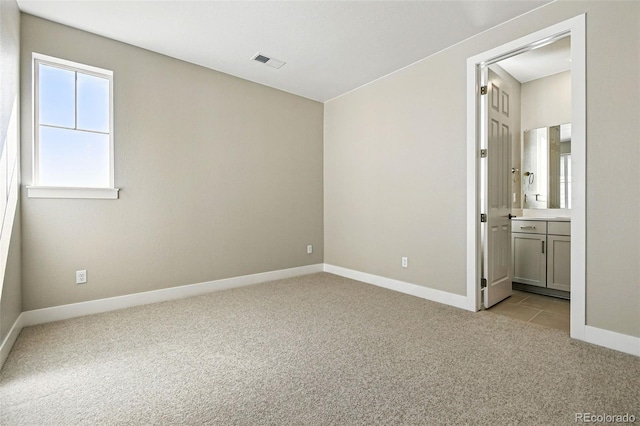 unfurnished bedroom featuring connected bathroom, light carpet, visible vents, and baseboards