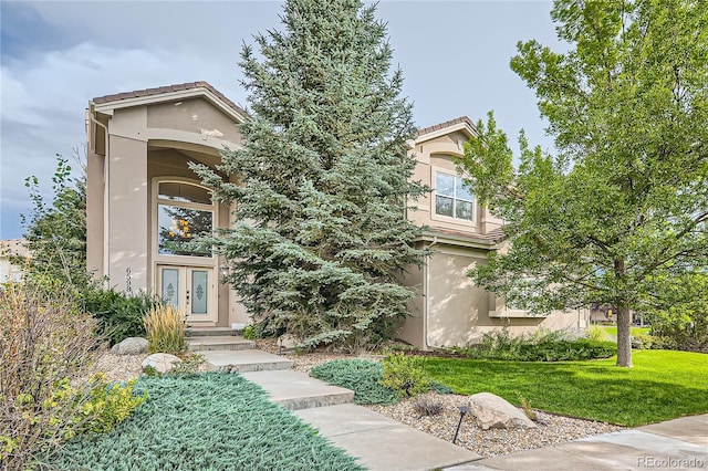 doorway to property with a lawn, stucco siding, and french doors