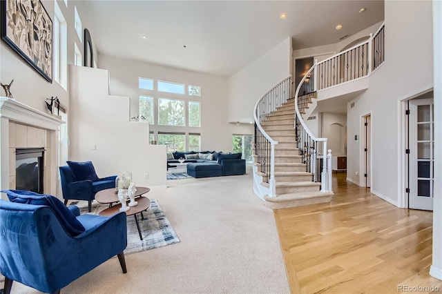 living area with baseboards, stairs, a high ceiling, and a tile fireplace