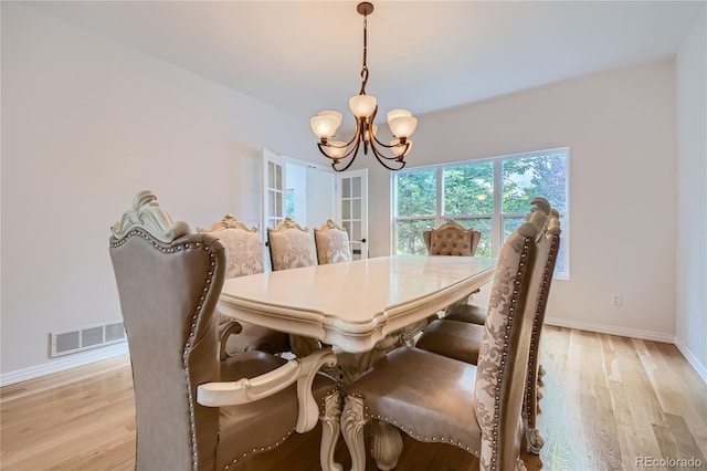 dining area featuring baseboards, light wood-style flooring, a chandelier, and visible vents