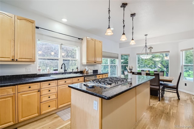kitchen with a sink, light wood finished floors, light brown cabinetry, and stainless steel appliances