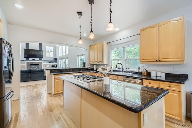kitchen with light brown cabinets, stainless steel appliances, and light wood finished floors
