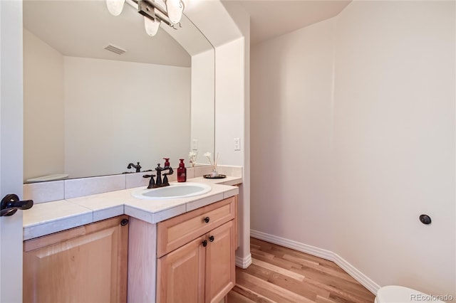 bathroom featuring vanity, baseboards, wood finished floors, and visible vents