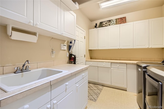 laundry area with light floors, a sink, cabinet space, and washer and dryer