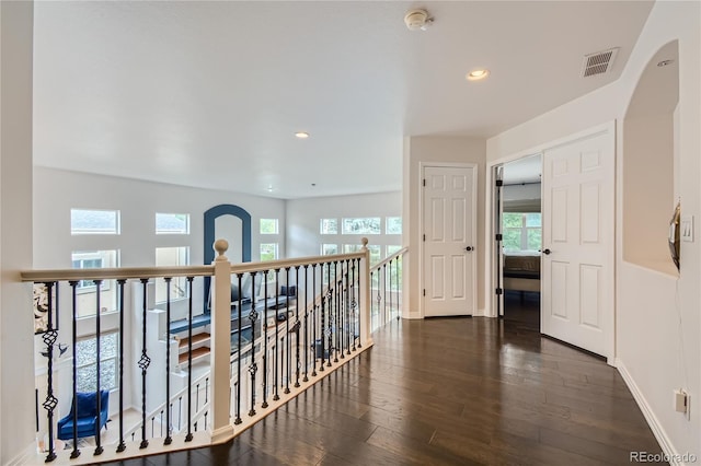 hallway featuring arched walkways, an upstairs landing, hardwood / wood-style flooring, and visible vents