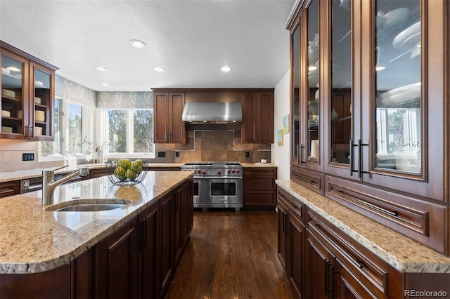 kitchen with dark wood-type flooring, sink, light stone counters, double oven range, and wall chimney range hood