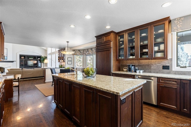 kitchen with a center island, stainless steel dishwasher, paneled fridge, pendant lighting, and light stone countertops