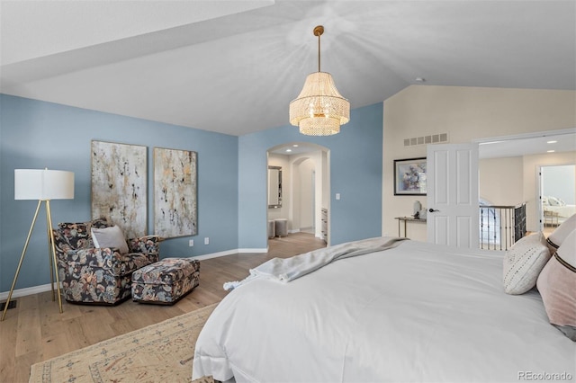 bedroom featuring lofted ceiling, hardwood / wood-style flooring, and ensuite bath