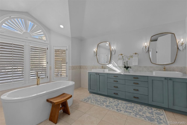 bathroom with lofted ceiling, tile patterned flooring, tile walls, vanity, and a tub