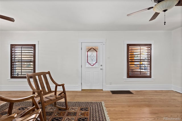 foyer featuring ceiling fan, baseboards, wood finished floors, and ornamental molding