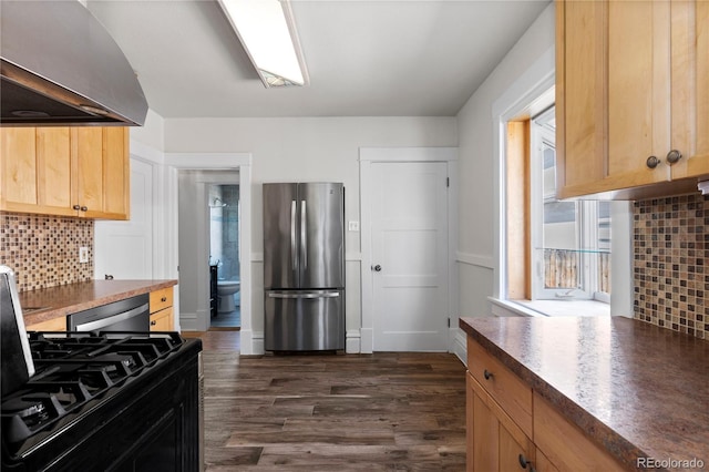 kitchen featuring backsplash, dark wood finished floors, freestanding refrigerator, wall chimney exhaust hood, and dishwasher