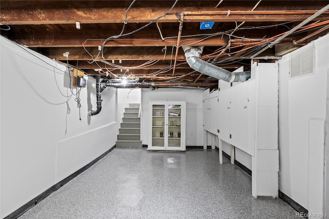 unfinished basement featuring stairs and baseboards