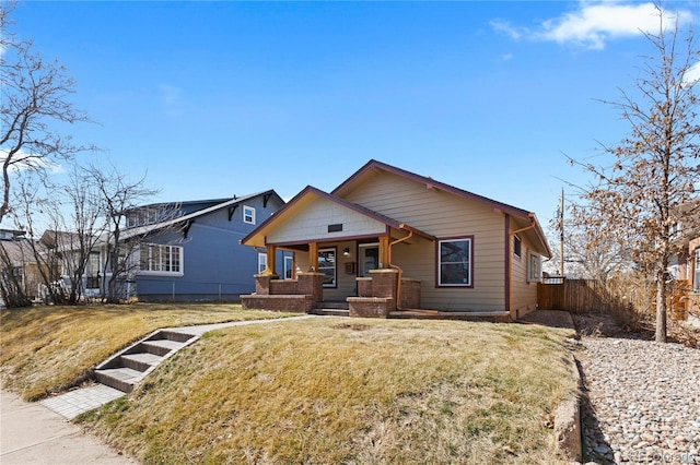 view of front of property with covered porch, a front yard, and fence