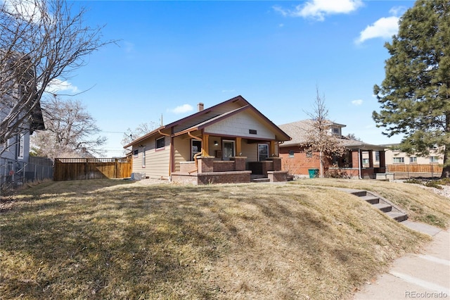 back of property with a lawn, a porch, and fence