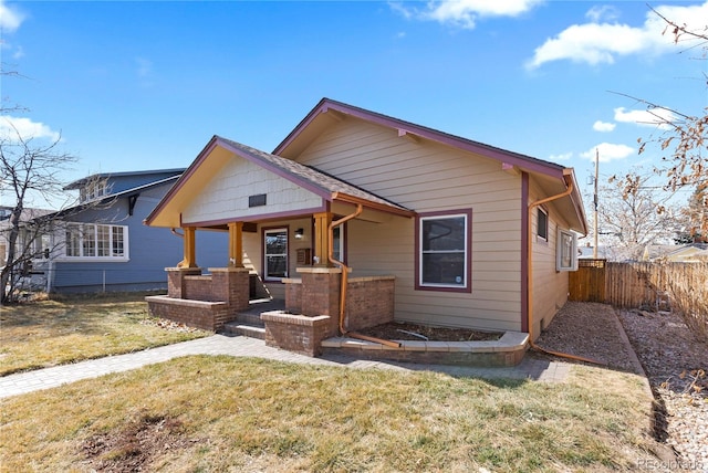 bungalow with a porch, a front lawn, and fence