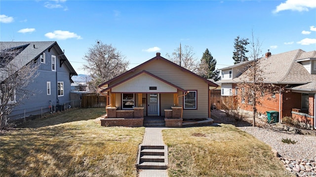 bungalow-style house featuring a porch, a front lawn, and fence