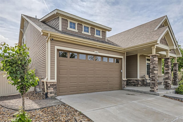 5495 Espana Ct, Denver, CO 80249 - craftsman-style house with stone siding, driveway, roof with shingles, and a porch