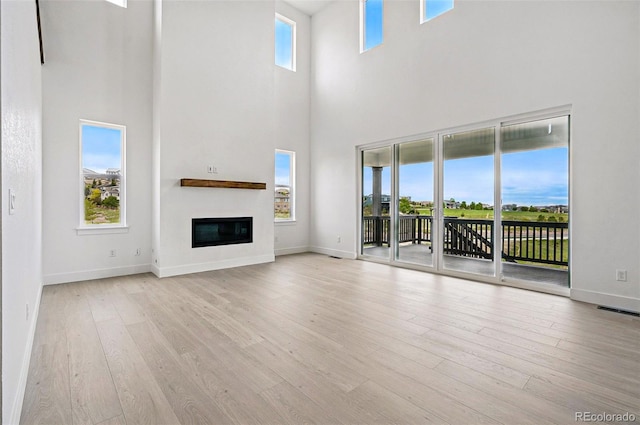 9382 Quaker St, Arvada, CO 80007 - unfurnished living room featuring a high ceiling, wood finished floors, a glass covered fireplace, and baseboards
