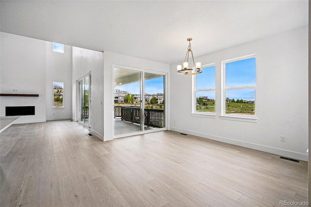 9382 Quaker St, Arvada, CO 80007 - unfurnished living room featuring a chandelier, light wood-style floors, and healthy amount of natural light