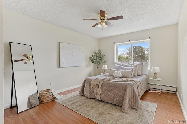 9650 Huron St Unit 12, Thornton, CO 80260 - bedroom with a baseboard heating unit, light wood-style floors, a textured ceiling, baseboards, and ceiling fan