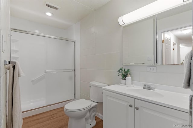 9650 Huron St Unit 12, Thornton, CO 80260 - bathroom featuring toilet, a shower stall, vanity, tile walls, and wood finished floors