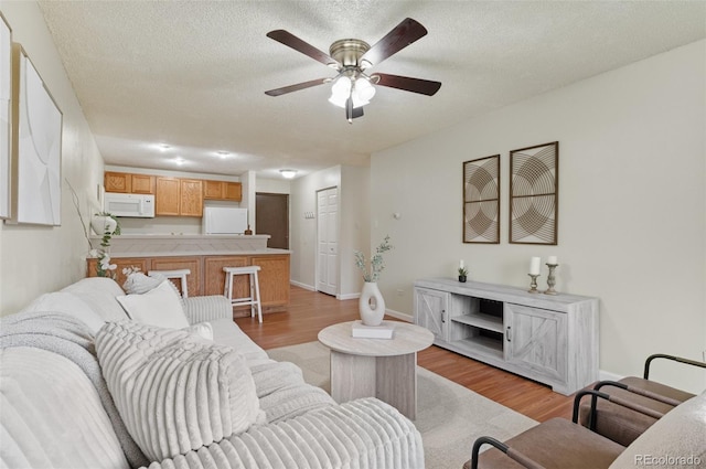 9650 Huron St Unit 12, Thornton, CO 80260 - living room featuring light wood-style flooring, a ceiling fan, a textured ceiling, and baseboards