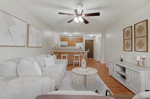 9650 Huron St Unit 12, Thornton, CO 80260 - living room with light wood finished floors, ceiling fan, a textured ceiling, and baseboards