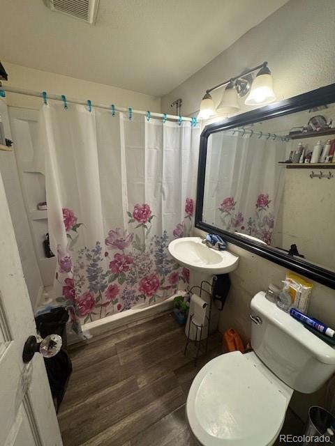 bathroom featuring a sink, visible vents, a shower with shower curtain, and wood finished floors