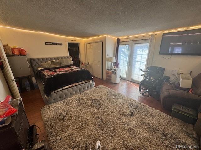 bedroom with access to exterior, wood finished floors, and a textured ceiling