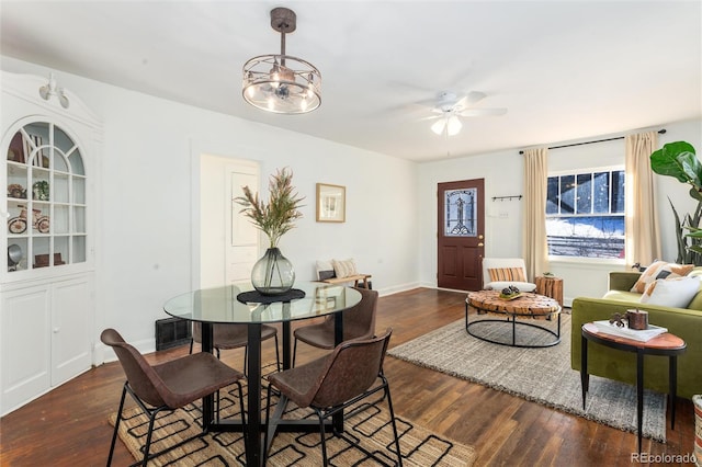 dining area with dark hardwood / wood-style flooring and ceiling fan with notable chandelier