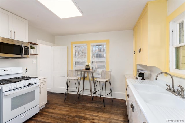 kitchen featuring dark hardwood / wood-style flooring, white cabinetry, white gas stove, and sink