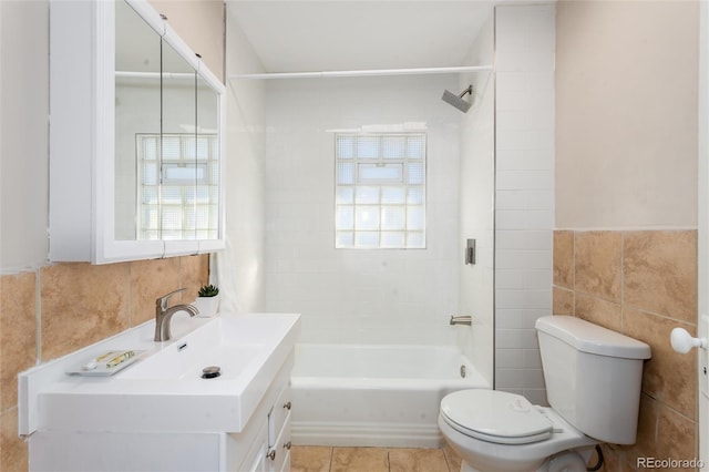 full bathroom with tiled shower / bath combo, tile patterned flooring, toilet, vanity, and tile walls