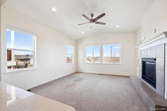 unfurnished living room featuring lofted ceiling, light colored carpet, a tile fireplace, and ceiling fan