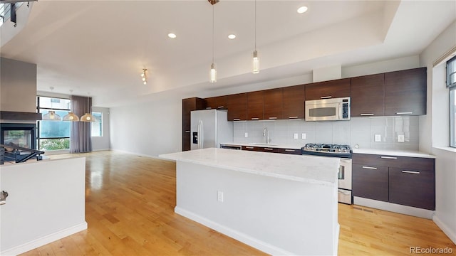 kitchen featuring decorative backsplash, a kitchen island, pendant lighting, and appliances with stainless steel finishes