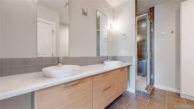 bathroom with tile patterned floors, vanity, decorative backsplash, and a shower with door