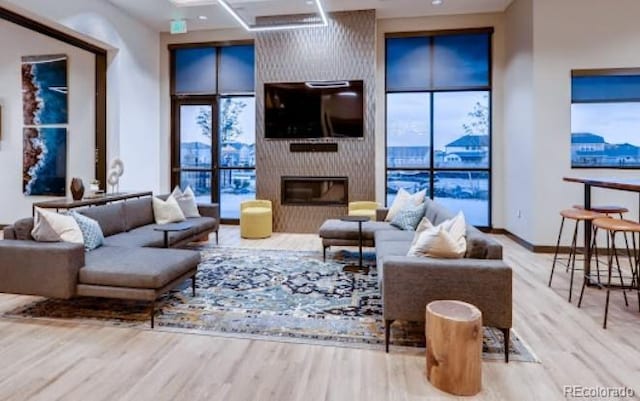 living room with baseboards, a large fireplace, wood finished floors, and a healthy amount of sunlight