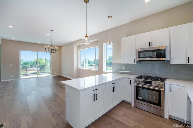 kitchen with kitchen peninsula, appliances with stainless steel finishes, white cabinetry, and hanging light fixtures