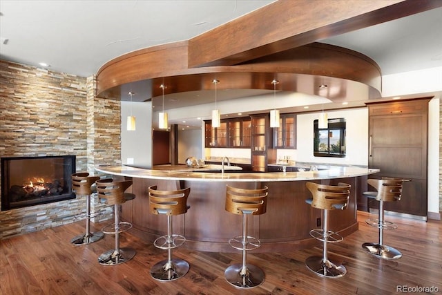 bar featuring a fireplace, decorative light fixtures, and dark wood-type flooring