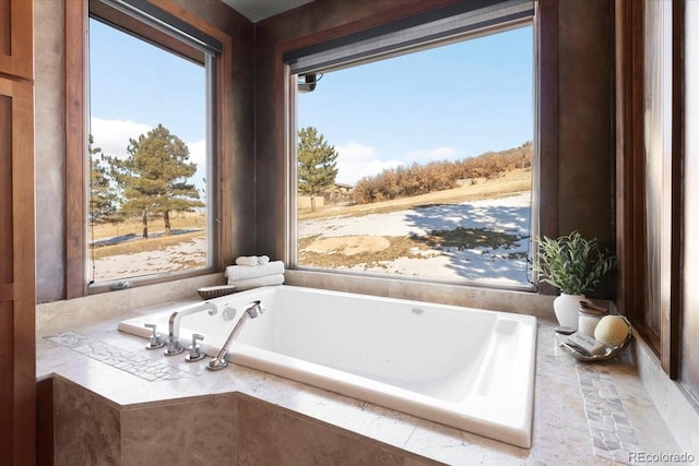 bathroom featuring a relaxing tiled tub and a wealth of natural light