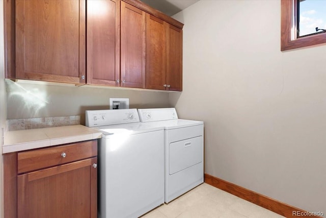 clothes washing area with cabinets and washing machine and clothes dryer