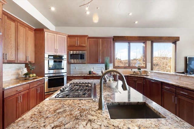 kitchen featuring light stone counters, appliances with stainless steel finishes, sink, and tasteful backsplash