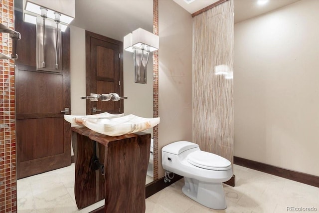 bathroom featuring baseboards, vanity, and toilet