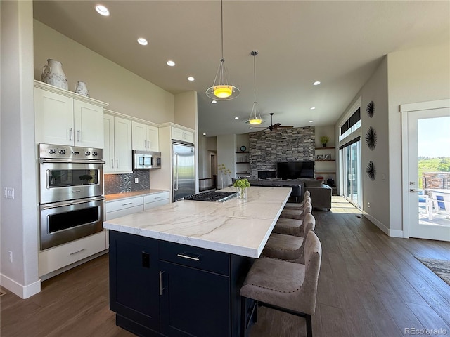 3125 Red Kit Rd, Franktown, CO 80116 - kitchen featuring stainless steel appliances, a center island, open floor plan, white cabinets, and dark wood finished floors