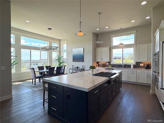 3125 Red Kit Rd, Franktown, CO 80116 - kitchen with stainless steel gas stovetop, healthy amount of natural light, a kitchen island, white cabinetry, and recessed lighting