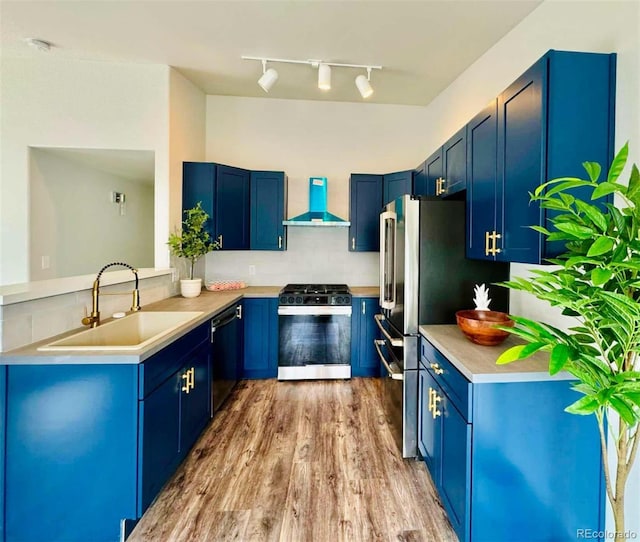 kitchen with sink, dishwasher, gas range oven, blue cabinets, and wall chimney exhaust hood