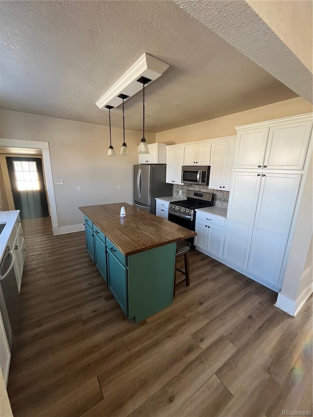 kitchen featuring stainless steel appliances, butcher block countertops, a kitchen island, and white cabinets