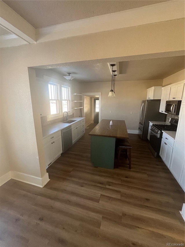 kitchen featuring appliances with stainless steel finishes, white cabinets, a kitchen island, and hanging light fixtures