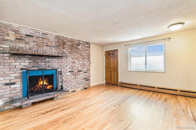 unfurnished living room featuring baseboards, a baseboard radiator, wood finished floors, a textured ceiling, and a brick fireplace